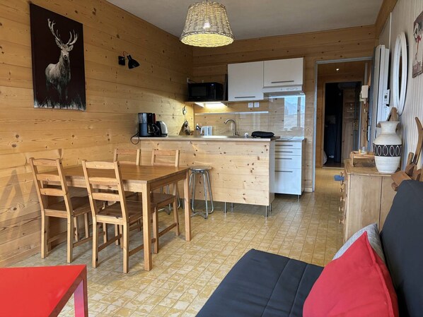 A wooden interior with a dining area, kitchen, and a sofa. - Charming functional apartment near the town center, balcony and free parking (Villard-de-Lans)