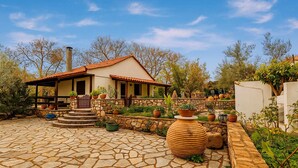 Una casa amb un pati de pedra, una terrassa de fusta i plantes en testos.