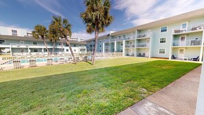 Ein mehrstöckiges Hotel mit Swimmingpool, Außenbereich und Palmen.