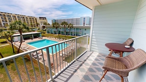 A balcony with a view of a swimming pool, lounge chairs, and a table. - Venus 308 overlooking pool Easy Beach Access by RedAwning (Fort Walton Beach)