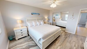 A bedroom with a large bed, two bedside tables, a ceiling fan, and a mirror. - Venus 306 is a 3 BR steps to Pool with easy beach access - sleeps 9 by RedAwning (Fort Walton Beach)