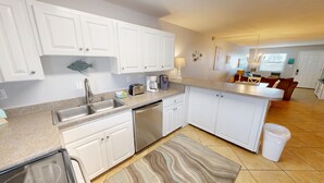 A modern kitchen with white cabinets, stainless steel appliances, and a granite countertop. - Venus 306 is a 3 BR steps to Pool with easy beach access - sleeps 9 by RedAwning (Fort Walton Beach)
