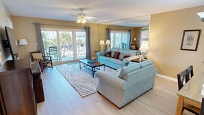 A spacious living room with a sofa, coffee table, and a dining area with a glass table.