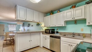 A kitchen with white cabinets, a dishwasher, a microwave, and a stove.