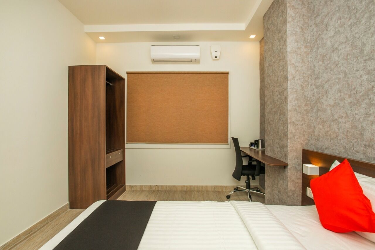 Una habitación de hotel con cama, escritorio, armario y aire acondicionado instalado en la pared.