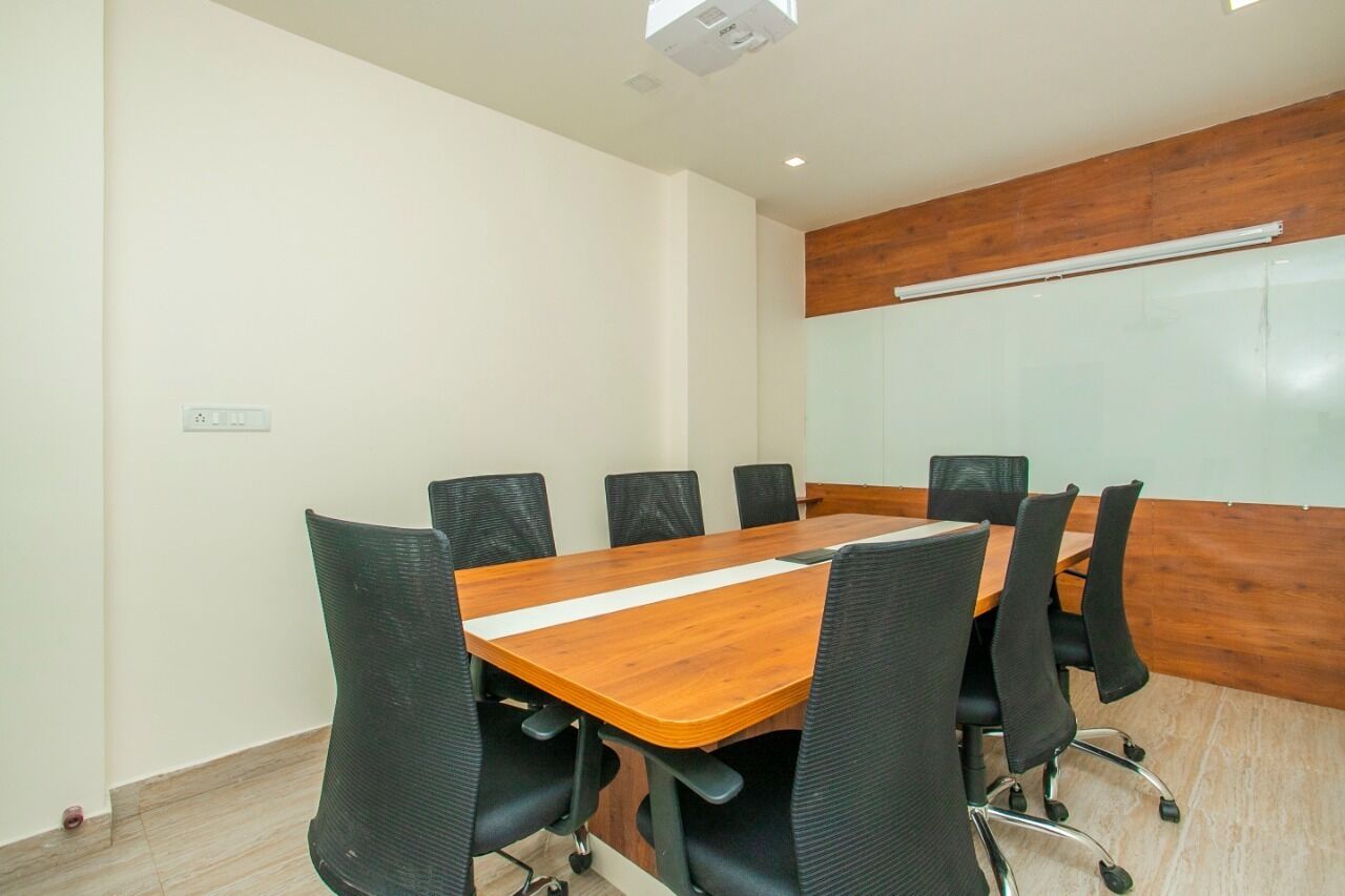 Un salón de conferencias con una mesa de madera, sillas negras y una pizarra en la pared.