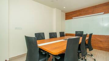 Un salón de conferencias con una mesa de madera, sillas negras y una pizarra en la pared.