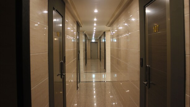 Un couloir doté de portes miroir, d’un plancher poli et d’un éclairage encastré.