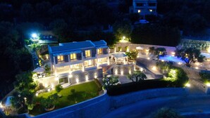 Un hotel de varios pisos con piscina, jardines ajardinados e iluminaci ón exterior.