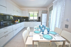 Enjoy meals in this well-equipped kitchen with stainless steel appliances and a dining area with a large window offering a view of the surrounding greenery.