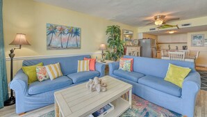 Een woonkamer met een blauwe bank, een salontafel en een eethoek met een tafel en stoelen.