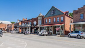 A street view with brick buildings, storefronts, and parked cars. - Frene Valley Guest House (Hermann)