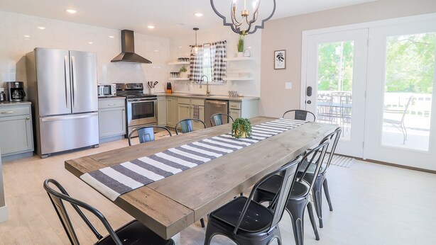 A modern kitchen with stainless steel appliances, a wooden dining table, and a chandelier. - Frene Valley Guest House (Hermann)