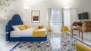 Une chambre d’hôtel équipée d’un lit, d’un bureau, d’une chaise, d’une télévision et d’une fenêtre avec des rideaux.