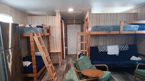 Habitació petita amb llits superposats, un sofà i una taula.