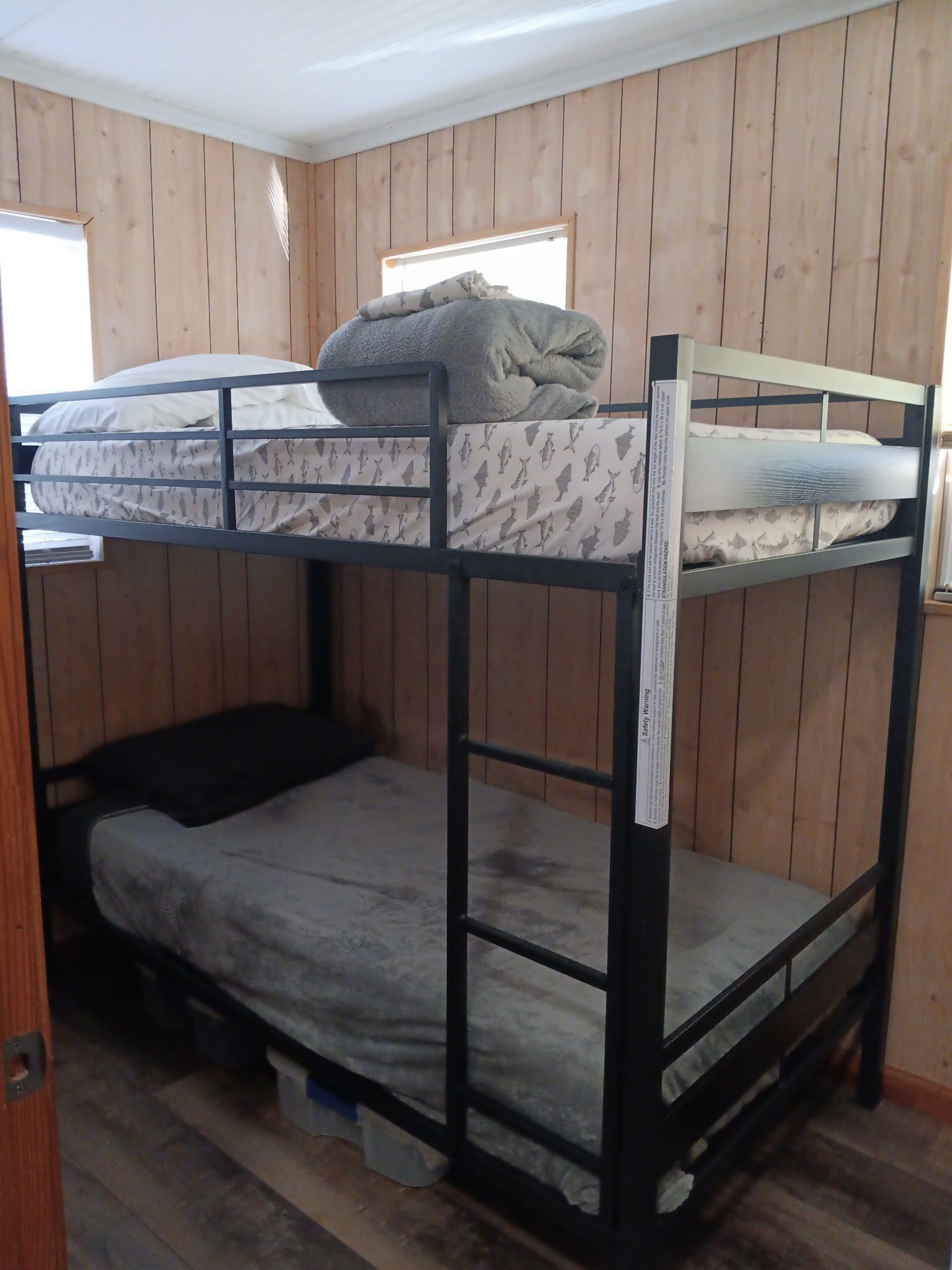 Un lit superposé avec un matelas à motifs, un oreiller et une barrière de sécurité.