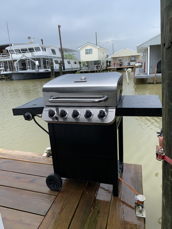 A portable grill on a wooden dock with a view of water and boats in the background. - HOUSEBOAT FOR RENT- Venice Marina- The “Get Reel”- JUST RENOVATED! (Venice)