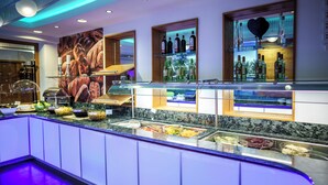 A buffet area with various food stations and a bar with shelves of bottles. - König Ludwig Designhotel (Altötting)