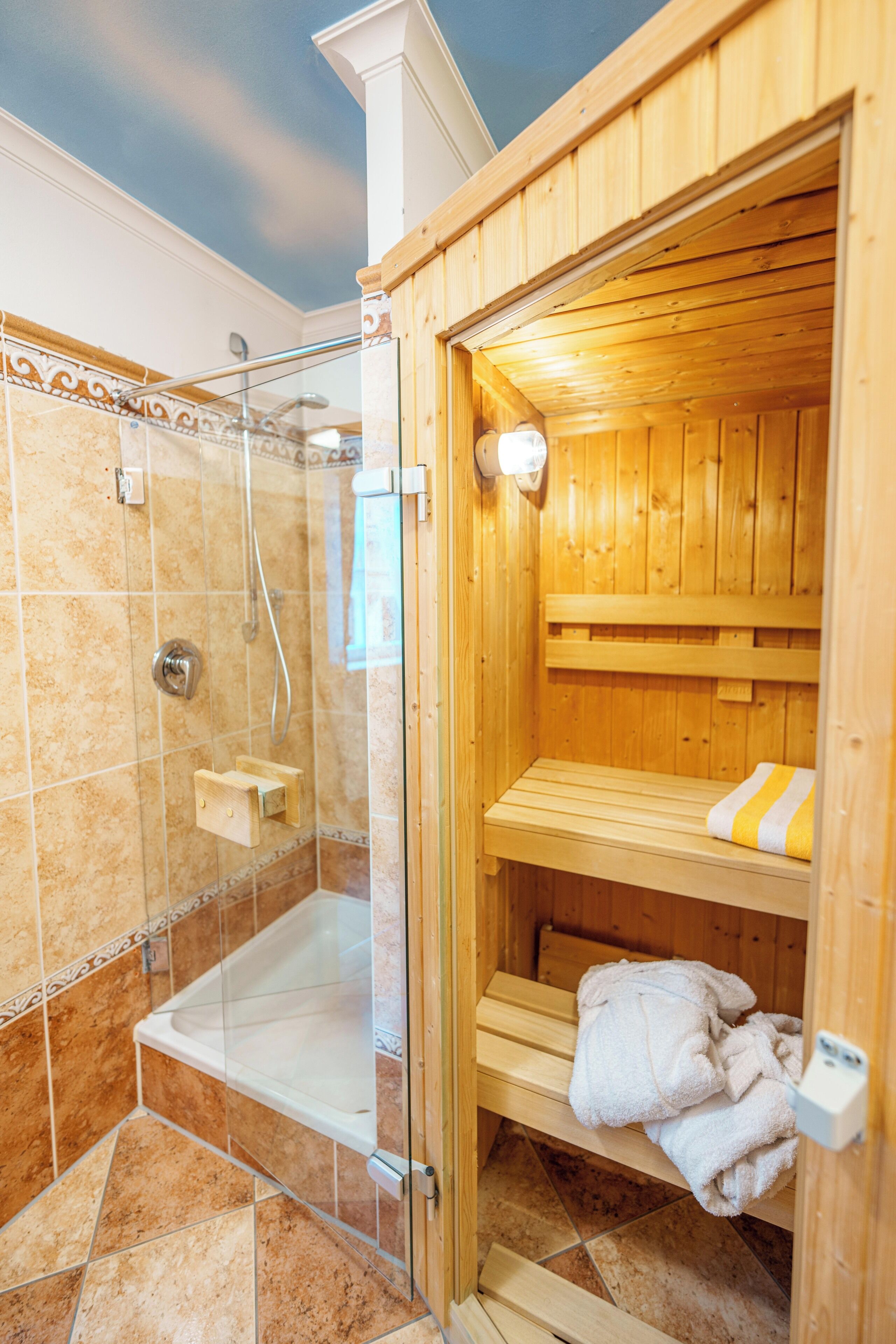 A sauna with a glass enclosure, a wooden bench, and a towel rack.