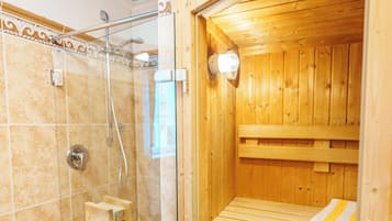 A sauna with a glass enclosure, a wooden bench, and a towel rack.