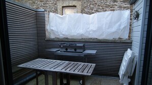 A small outdoor patio with a wooden table and a grill. - VILLA with garage and terrace 200 ml beaches parks and shops (Saint-Malo)