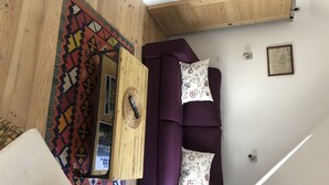 A living room with a purple sofa, a wooden coffee table, and a colorful rug. - VILLA with garage and terrace 200 ml beaches parks and shops (Saint-Malo)