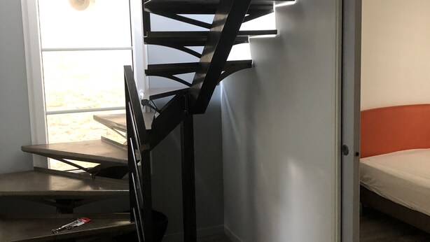 A modern interior with a spiral staircase, a bed, and a door leading to an outdoor area. - VILLA with garage and terrace 200 ml beaches parks and shops (Saint-Malo)