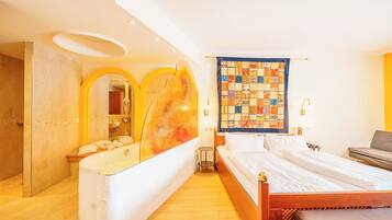 Ein Hotelzimmer mit einem hölzernen Bett, einem großen Spiegel, einem Badezimmer mit einer Badewanne und einer Wanddecke.