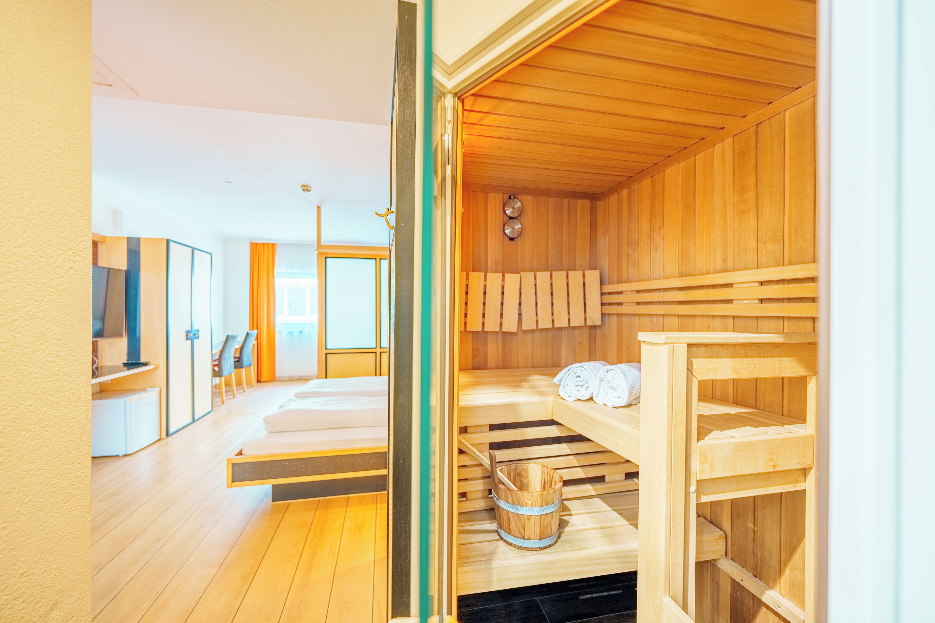 Un cuarto de sauna con bancos de madera, un perchero para toallas y un cubo de madera.