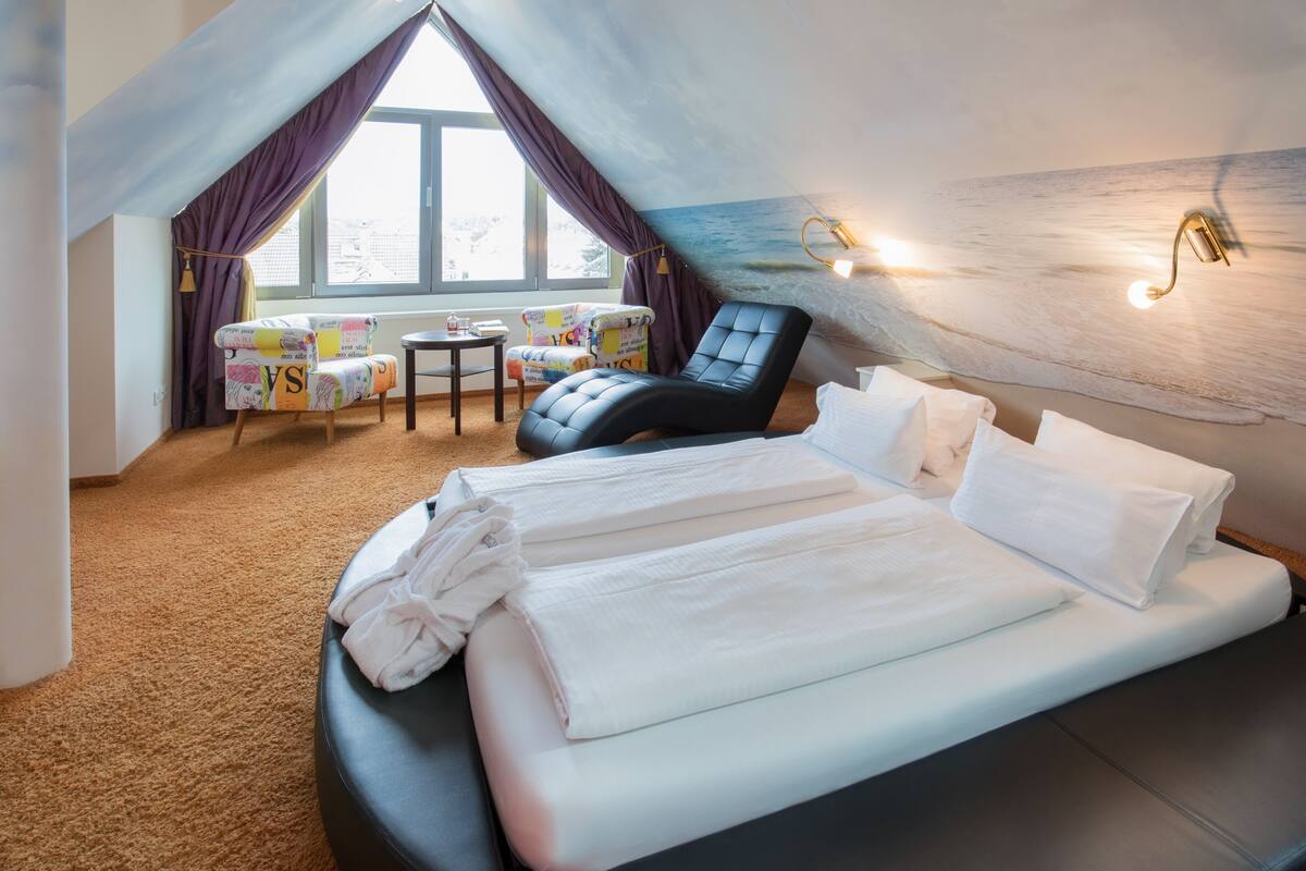 Une chambre d’hôtel avec un lit, une chaise, une petite table et une vue sur l’extérieur.