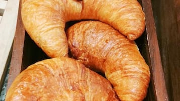 A wooden box containing several golden-brown croissants.