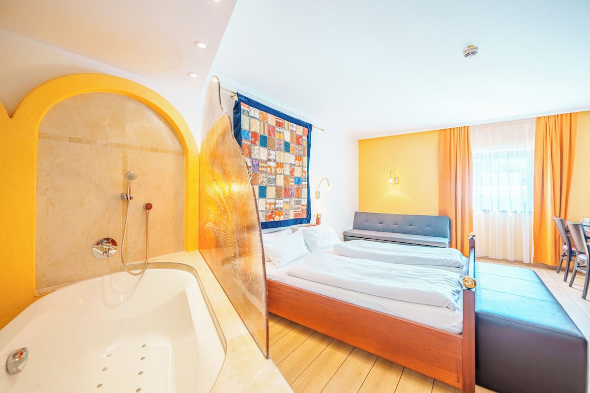 Une chambre d’hôtel avec une grande baignoire, un lit avec un cadre en bois et un rideau de douche matelassé.