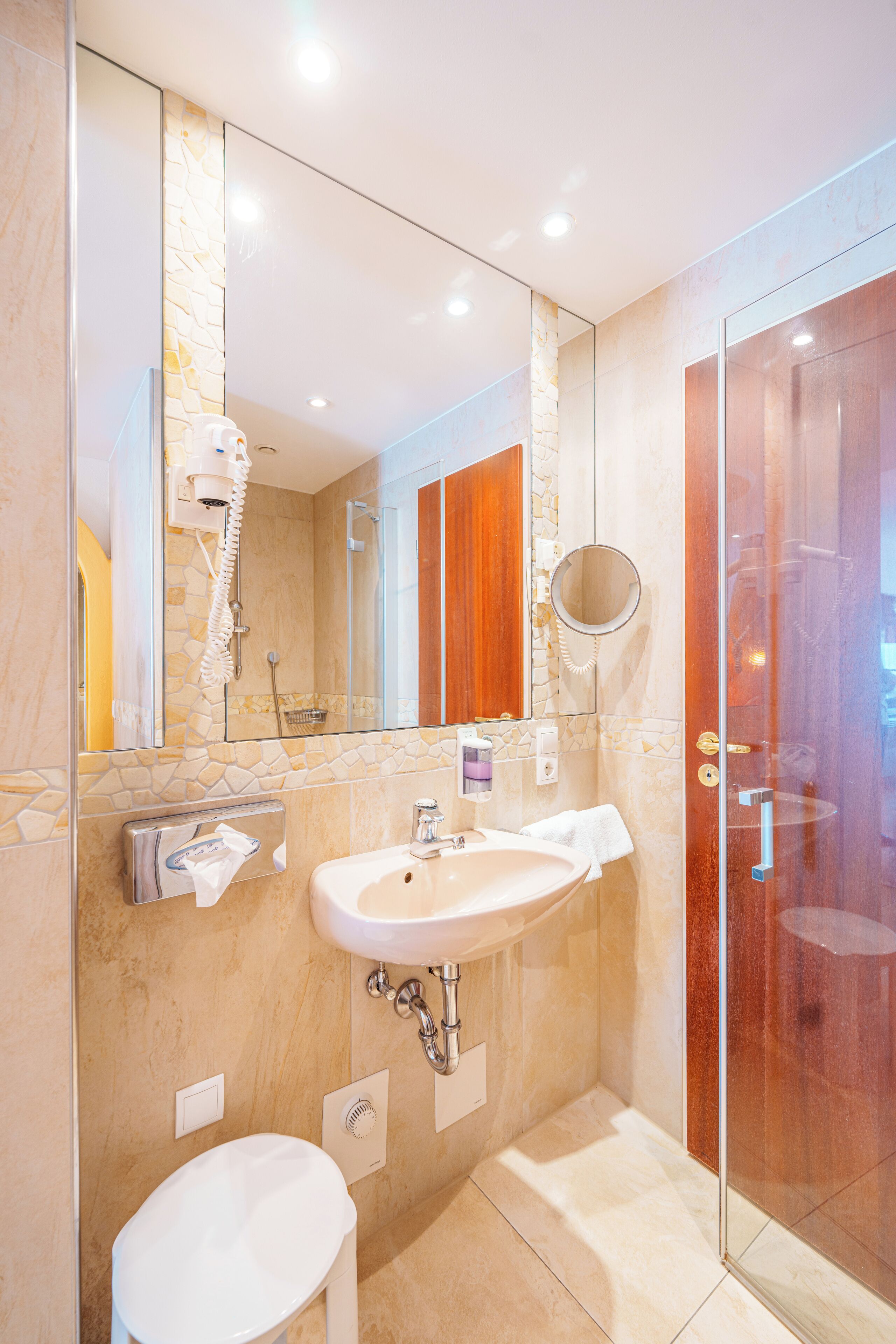A modern bathroom with a glass shower enclosure, a white sink, and a mirror above the sink.