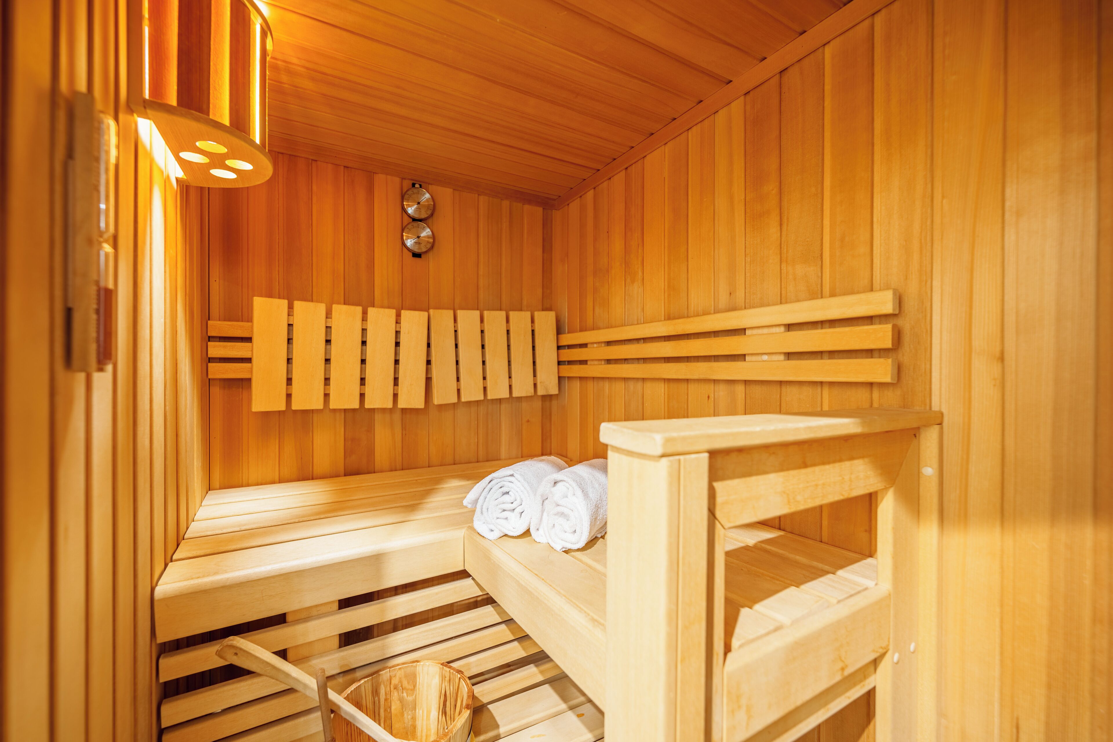 A sauna with wooden benches and benches, a towel rack, and a wooden wall.