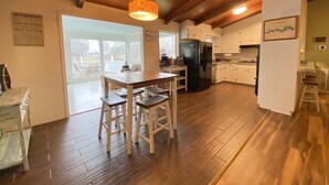 A spacious kitchen with wooden floors, a dining area with a table and chairs, and a view through the glass door to the outside. - Relax on Lake Bowen at our spacious 3-bedroom retreat (Inman)