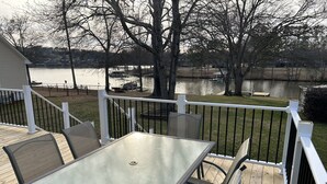A deck with a table and chairs, overlooking a lake with boats and a dock. - Relax on Lake Bowen at our spacious 3-bedroom retreat (Inman)