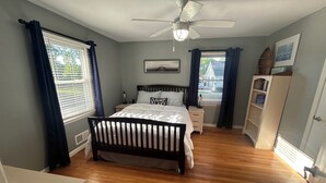 A bedroom with a bed, a nightstand, a dresser, a ceiling fan, and a window with curtains. - Relax on Lake Bowen at our spacious 3-bedroom retreat (Inman)