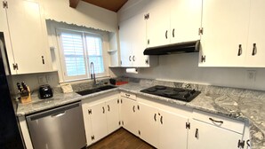 A kitchen with white cabinets, a black stove, and a window with blinds. - Relax on Lake Bowen at our spacious 3-bedroom retreat (Inman)