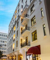 Ein mehrstöckiges Hotel mit Balkonen, einer roten Markise und beleuchteten Fenstern.