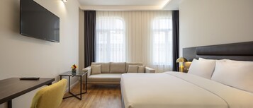 Ein Hotelzimmer mit Bett, Sofa, Schreibtisch und Fernseher.