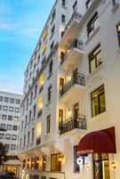 Un hotel a più piani con balconi, un tendone rosso e finestre illuminate.
