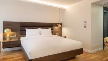 Une chambre d’hôtel moderne avec un grand lit, des tables de chevet, une lampe et une chaise.