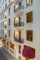 Ein mehrstöckiges Hotel mit Balkonen, großen Fenstern und einer roten Markise mit dem Namen des Hotels.