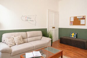 A room with a sofa, a coffee table, a bulletin board, and a door. - I Colori della Sicilia (Caltagirone)