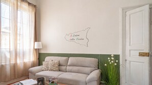 A living room with a sofa, a glass coffee table, a lamp, and a wall map. - I Colori della Sicilia (Caltagirone)