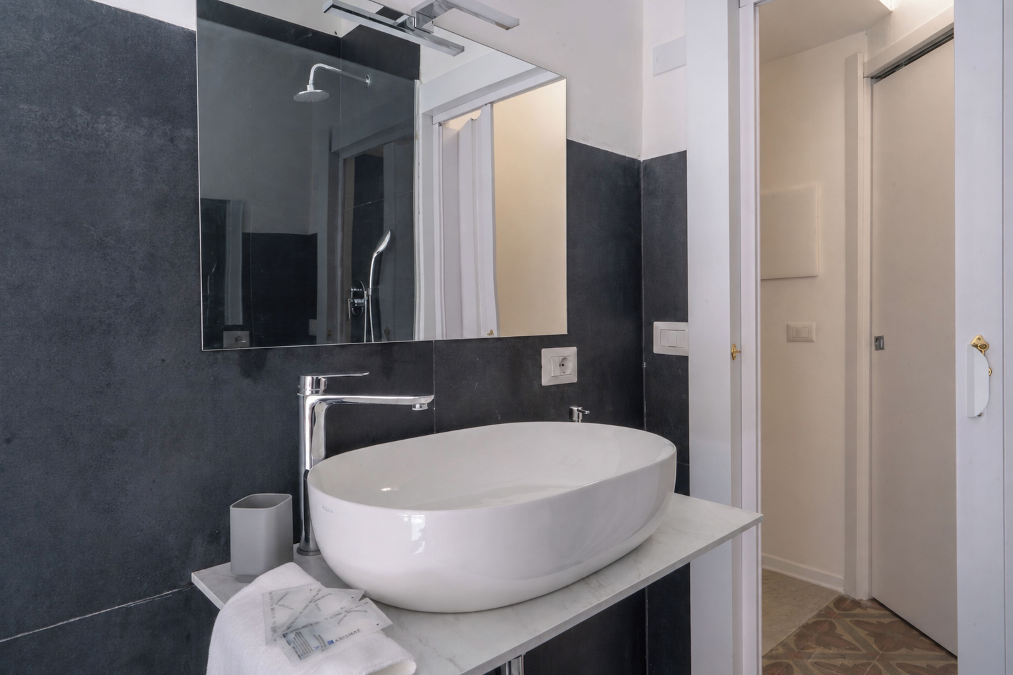 A modern bathroom with a large oval sink, a mirror, and a shower.