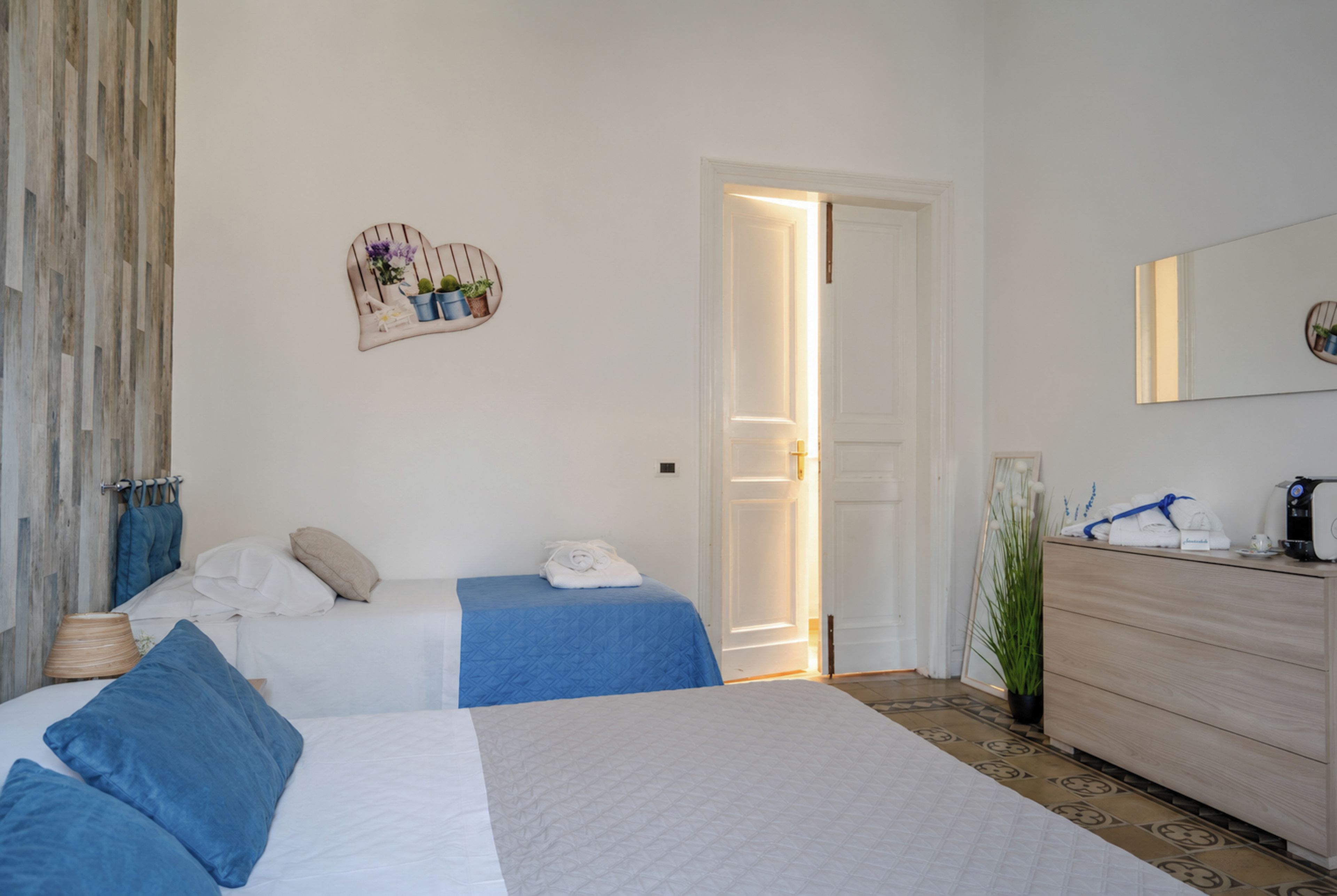 A hotel room with two beds, a dresser, a mirror, and a potted plant.