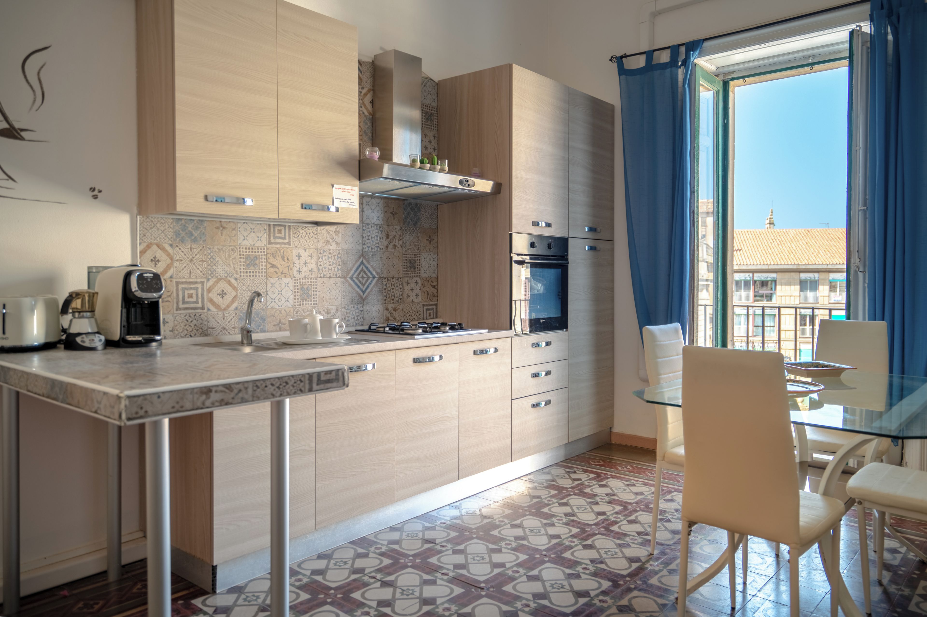 Una cocina moderna con estufa a gas, horno y comedor con mesa y sillas de vidrio.