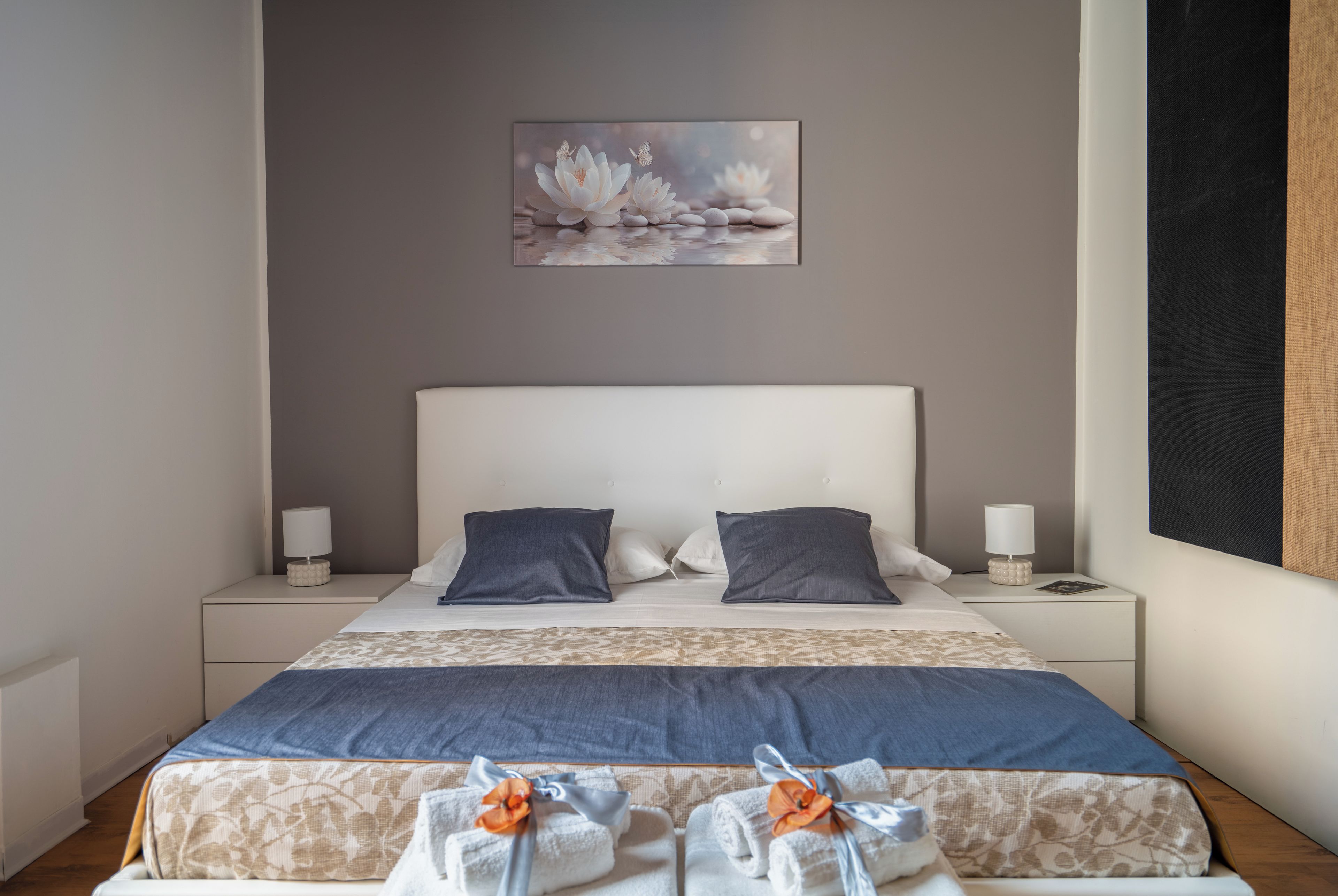 A neatly made bed with a patterned bedspread, two pillows, and a nightstand with a lamp.