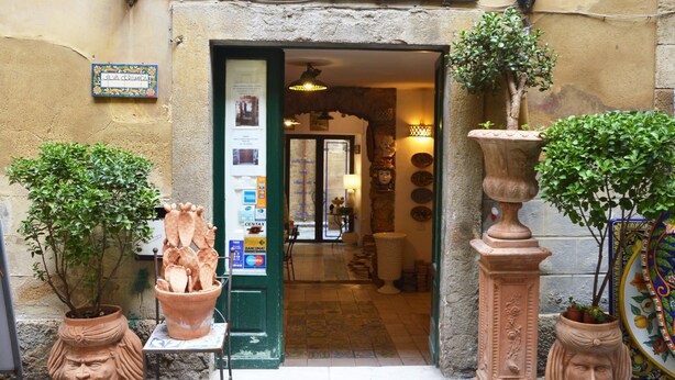 A ceramic shop entrance with a sign, potted plants, and a tiled floor. - I Colori della Sicilia (Caltagirone)